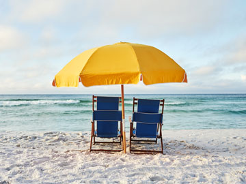 Beach chairs facing ocean with yellow umbrella