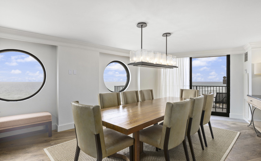 Formal dining space surrounded by windows overlooking the beach