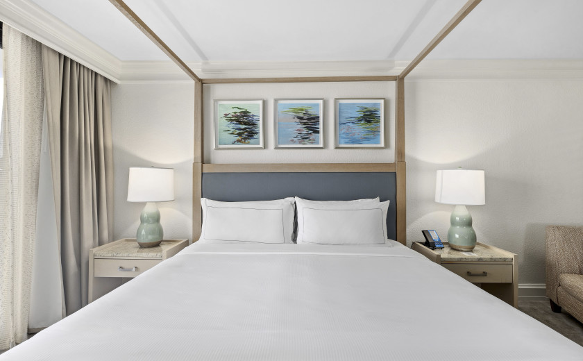 Large hotel bed with light blue lamps on two nightstands