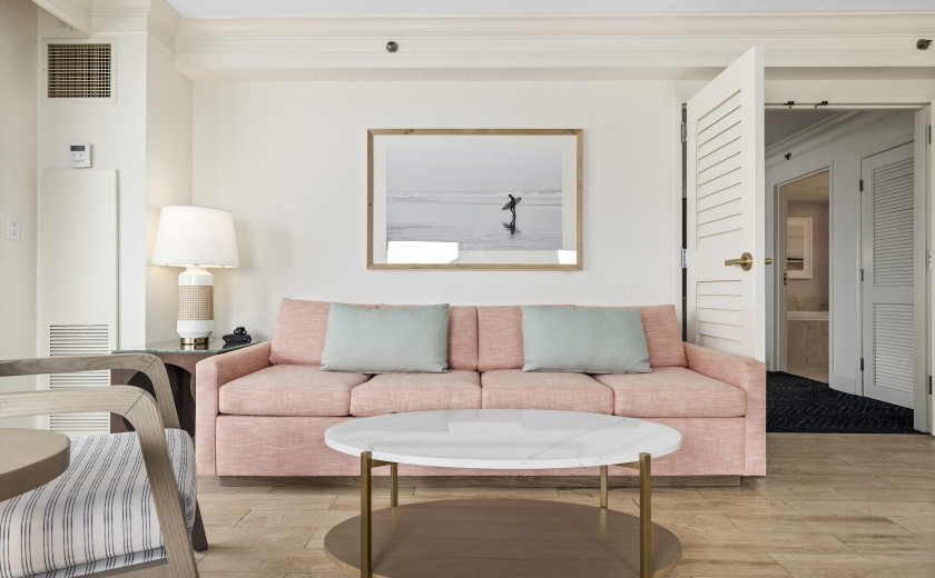 Pink couch with framed art of a surfer on the wall