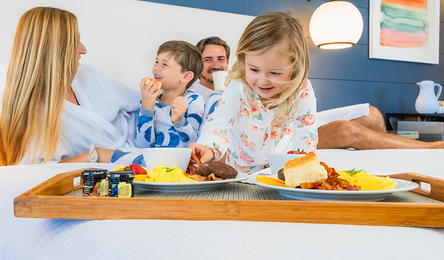 Family enjoying breakfast in bed on a vacation